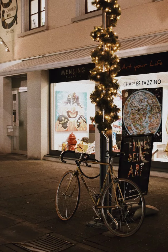 Photo of a Bicycle Parked on a Pole with Christmas Lights